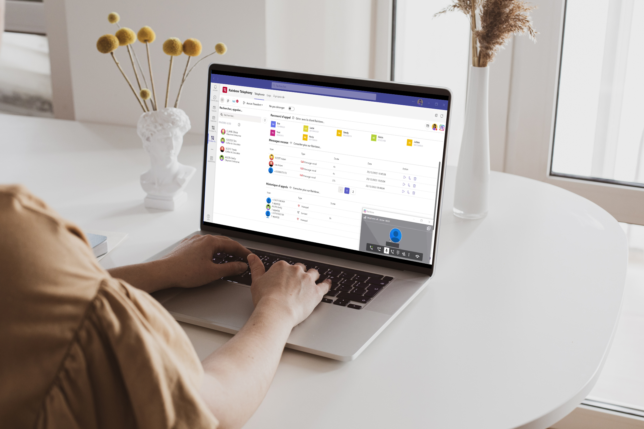 Woman using the Rainbow Telephony interface happily working with platform which fosters digital transformation and innovation woman typing on her laptop while using Rainbow Telephony for Microsoft Teams